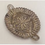 A silver filigree dish with scroll decoration. App