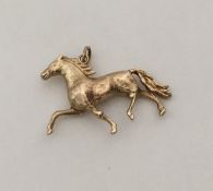An unusual 9 carat pendant in the form of a gallop