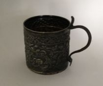 A heavy Indian silver mug decorated with animals.