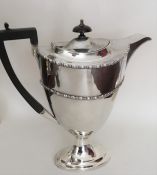 A large heavy silver hot water jug on spreading ov