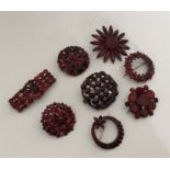 A collection of eight red Vauxhall glass brooches.