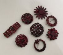A collection of eight red Vauxhall glass brooches.