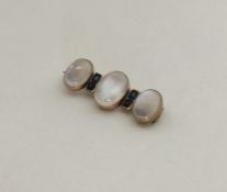 A stylish moonstone and sapphire brooch in gold fr