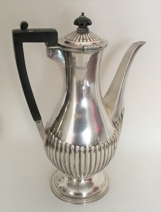 A heavy silver coffee pot of half fluted design. L