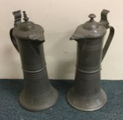 A pair of tall pewter flagons with hinged tops to