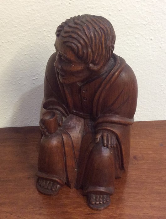 A small carved figure of an old man in seated posi