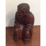 A small carved figure of an old man in seated posi
