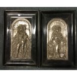 A pair of ebony framed plated wall plaques depicti
