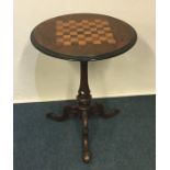 A Victorian burr walnut games table on three scrol