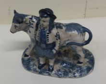 A Delft figure of a cow and farmer. Est. £50 - £80