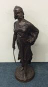 A tall bronze figure of a lady with sword on rugge