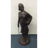 A tall bronze figure of a lady with sword on rugge