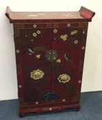 A red lacquered Chinese two door cupboard profusel