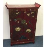A red lacquered Chinese two door cupboard profusel
