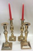 A pair of Antique brass square based candlesticks