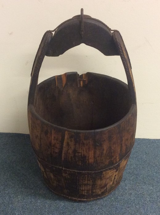 A large wooden milk pail with steel handle to loop