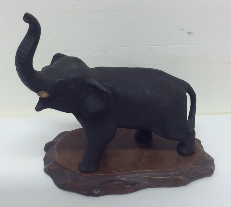 A cast bronze figure of an elephant on wooden base