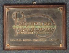 A rectangular brass engineer's plaque on wooden su