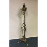 A tall brass Art Nouveau oil lamp on three spreadi