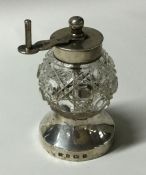 A silver and cut glass pepper grinder on spreading