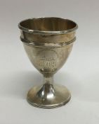 A Georgian silver egg cup decorated with a crest.