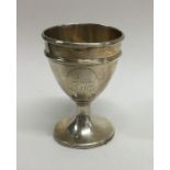 A Georgian silver egg cup decorated with a crest.