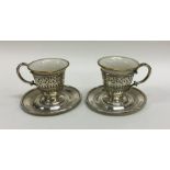 A pair of silver and porcelain cups and saucers. A