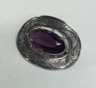 An oval silver brooch decorated with an amethyst.