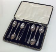 A set of six silver teaspoons and tongs in fitted