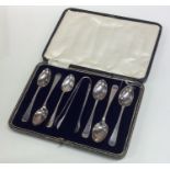 A set of six silver teaspoons and tongs in fitted