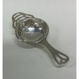 A stylish silver tea strainer with pierced decorat