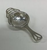 A stylish silver tea strainer with pierced decorat