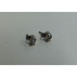 A pair of diamond stud earrings in rubover mounts.