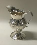 A Georgian silver cream jug with scroll decoration