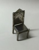 A miniature silver chair with engraved decoration.