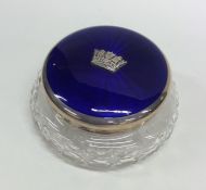 A circular silver and enamelled dressing table box