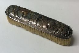 A silver embossed hairbrush decorated with cherubs