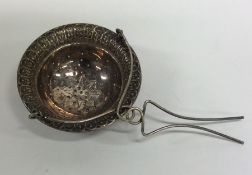 A Continental silver tea strainer with floral deco