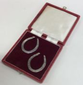 A pair of silver horseshoes contained within a fit