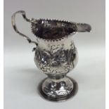 A Georgian embossed silver cream jug decorated wit