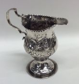 A Georgian embossed silver cream jug decorated wit