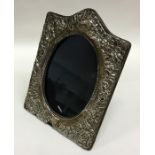 A shaped silver embossed frame decorated with flow