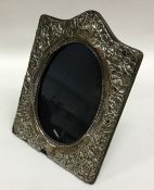 A shaped silver embossed frame decorated with flow