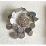 A silver charm bracelet together with a medallion.
