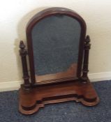 A mahogany dome top toilet mirror with shaped edge