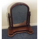 A mahogany dome top toilet mirror with shaped edge