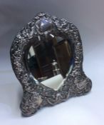 An Edwardian silver heart shaped mirror decorated