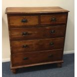 A pitch pine chest of five drawers on bun feet. Es