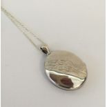 A large oval silver locket with engraved decoratio