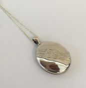 A large oval silver locket with engraved decoratio